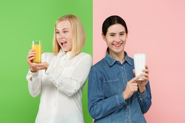 Diet. Dieting concept. Healthy Food. Beautiful Young Women choosing between fruit orange juice and unhelathy carbonated sweet drink