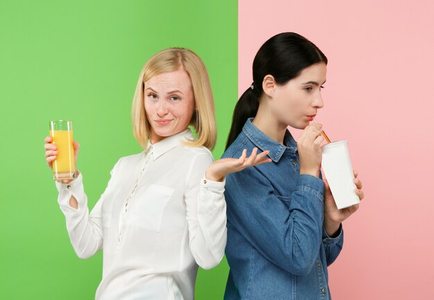 Рацион питания. Концепция диеты. Здоровая пища. Beautiful Young Women выбирают между фруктовым апельсиновым соком и газированным сладким напитком
