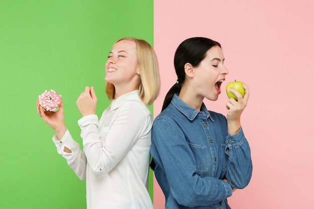 Diet. Dieting concept. Healthy Food. Beautiful Young Women choosing between fruits and unhelathy cake