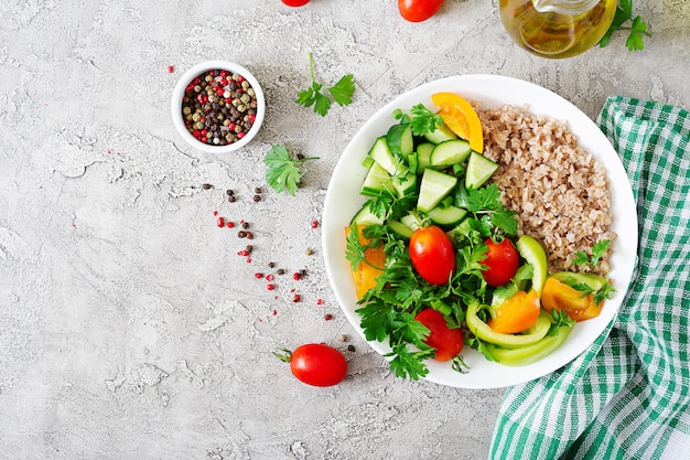 免费照片饮食菜单。健康的素食沙拉新鲜蔬菜,西红柿,黄瓜、甜辣椒和粥在碗里。素食食物。平的。俯视图