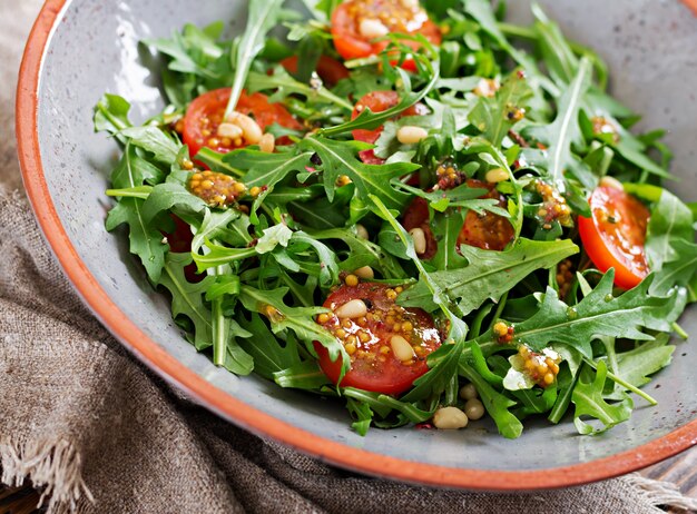 Dietary menu. Vegan cuisine. Healthy salad with arugula, tomatoes and pine nuts.