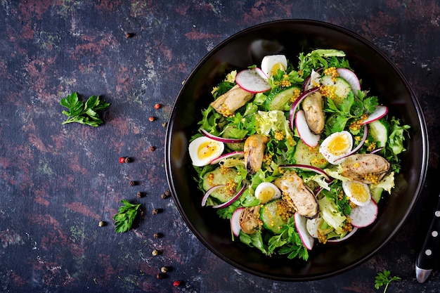 Dietary salad with mussels, quail eggs, cucumbers, radish and lettuce. Healthy food. Seafood salad. Top view. Flat lay.