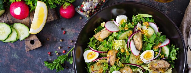 Dietary salad with mussels, quail eggs, cucumbers, radish and lettuce. Healthy food. Seafood salad. Top view. Flat lay.