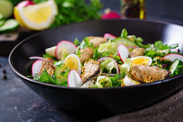 Диетический салат с мидиями, перепелиными яйцами, огурцами, редисом и салатом. Здоровая пища. Салат из морепродуктов.