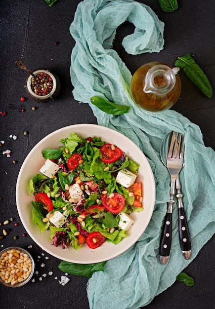 Dietary salad with tomatoes, feta, lettuce, spinach and pine nuts. Top view. Flat lay.