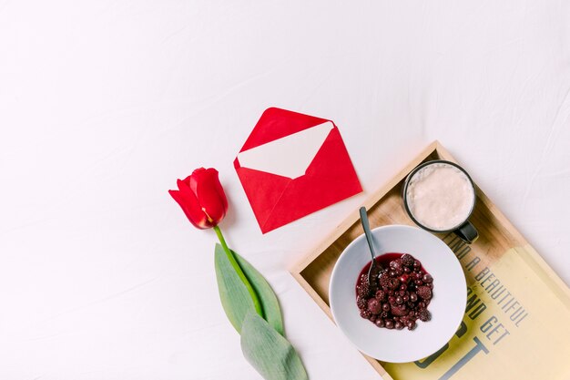 Different berries on plate with red tulip