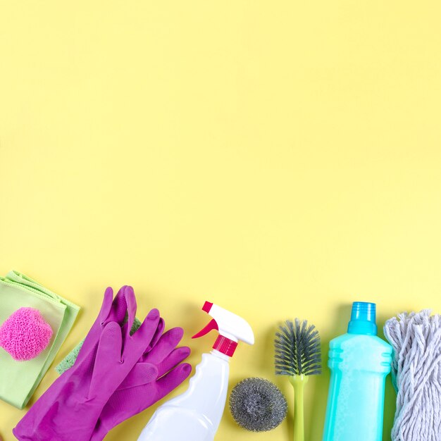 Different cleaning equipments on yellow backdrop
