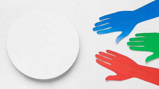 Different colored paper hands next to a white circle