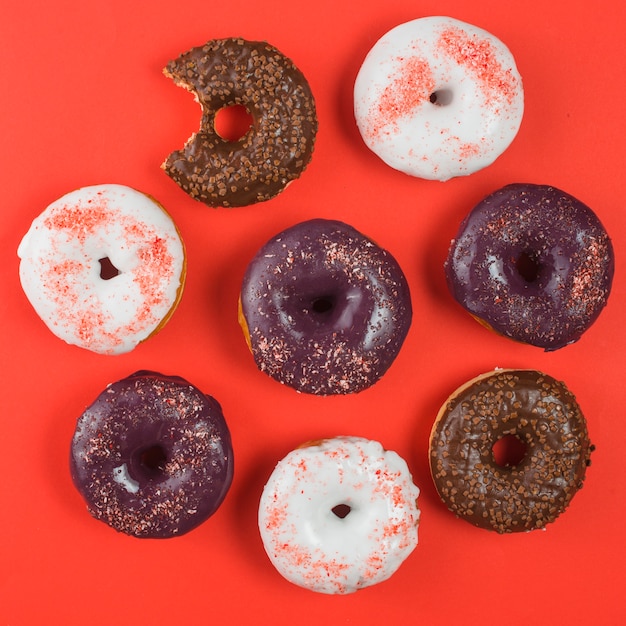 Различные красочные матовое пончики с укусом знак на красном фоне
