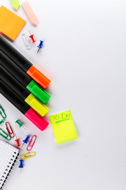 Different colorful markers with business office accessories on white office table. Top View.