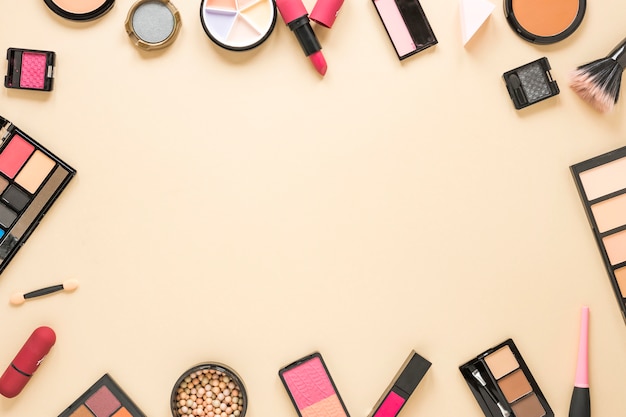 Different cosmetics types scattered on beige table 