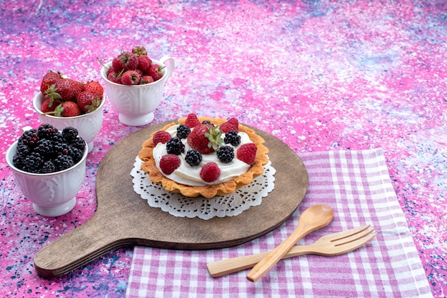 different delicious cakes with cream and fresh berries on light purple