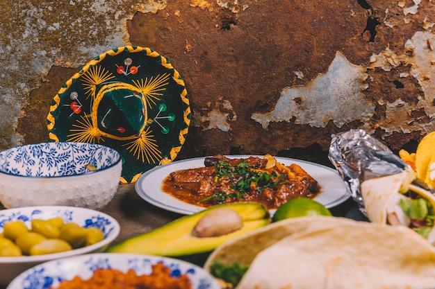 Different delicious mexican dishes over rusty background with mexican hat