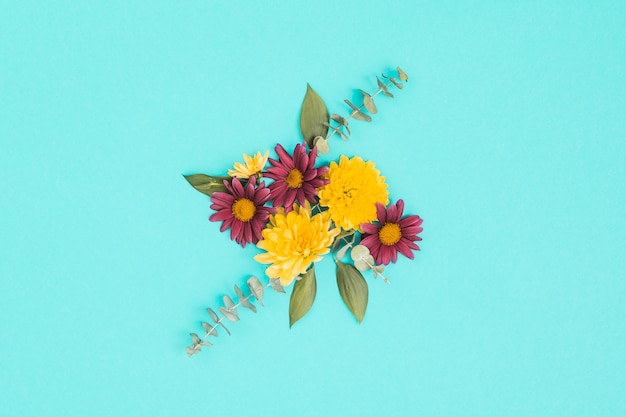 Different flowers with green leaves on table