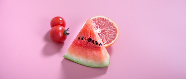 Different fruits and vegetables on a colored wall.