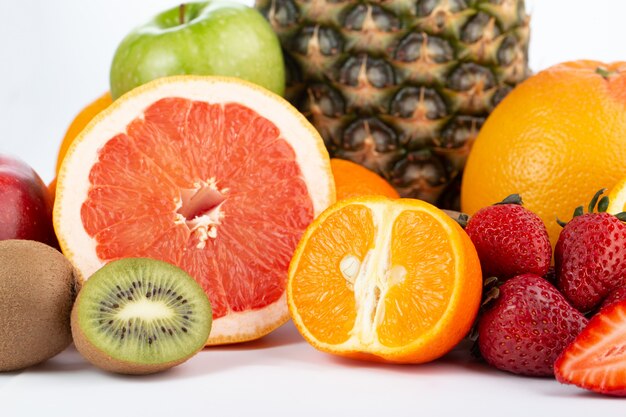 Различные фрукты, богатые витаминами, свежие спелые, сочные, изолированные на белом полу