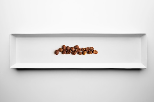 Different grades of artisan professional roasting coffee isolated on white plate, top view