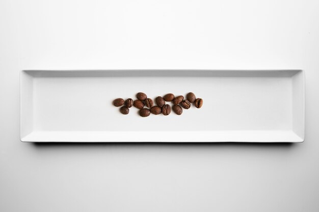 Different grades of artisan professional roasting coffee isolated on white plate, top view