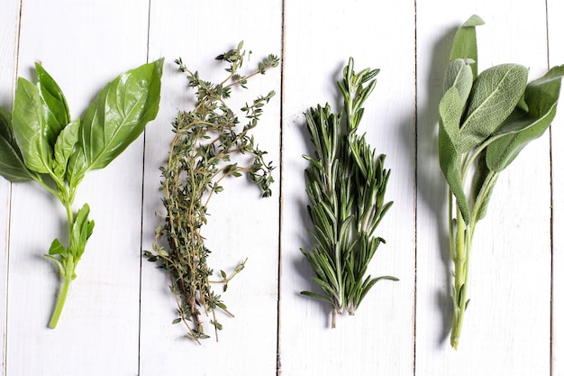 Different herbs in white wooden table, top view