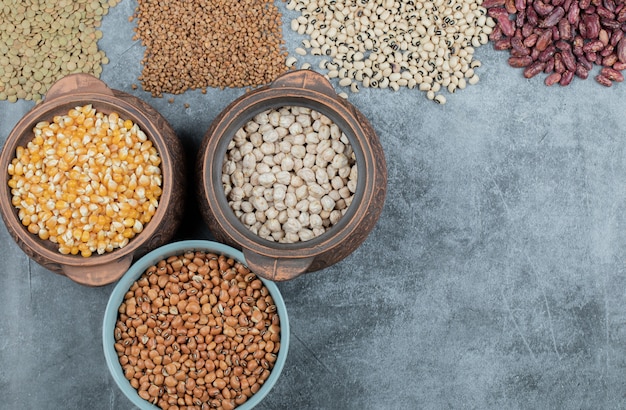 Different kinds of bean seeds, lentil, peas in dishes on black .