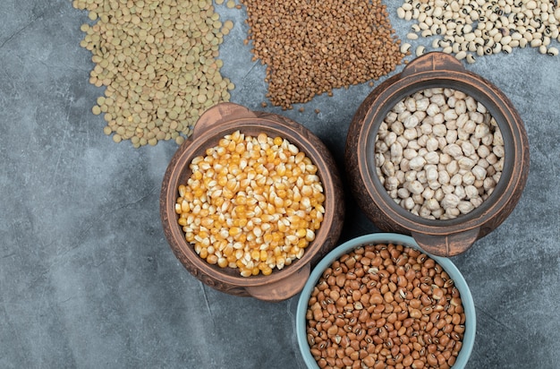 Different kinds of bean seeds, lentil, peas in dishes on black .