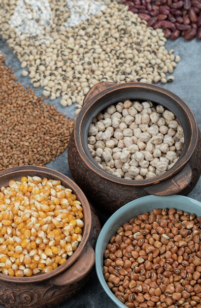 Different kinds of bean seeds, lentil, peas in dishes on black .