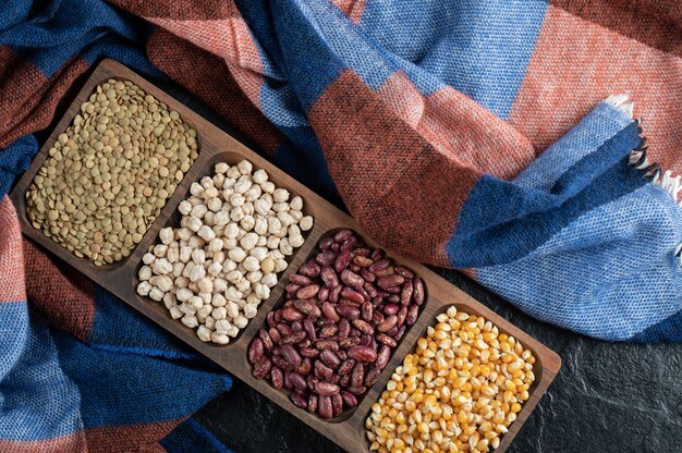 Different kinds of beans on wooden plates.