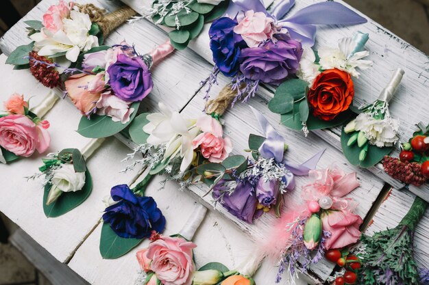 Different kinds of boutonnieres lie on white table