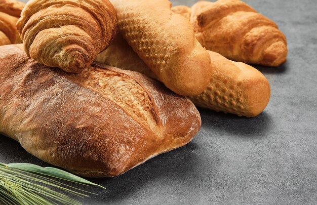 Different kinds of bread rolls on gray board closeup Kitchen or poster design for a local bakery Baguette croissant and ciabatta various types of freshly baked bread