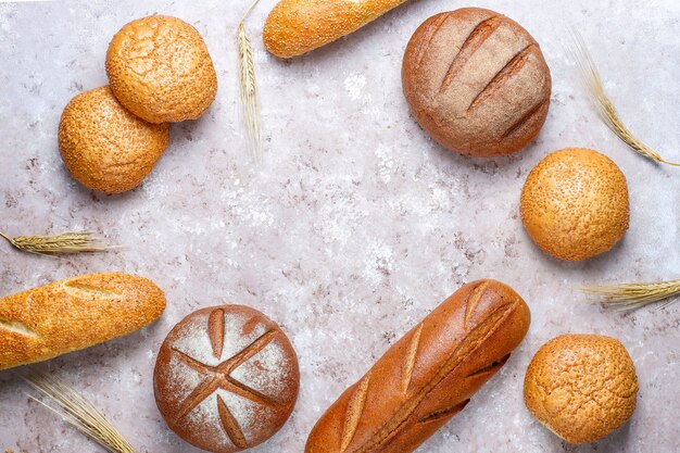 Different kinds of fresh bread as background, top view