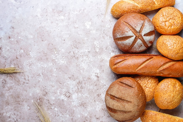 Different kinds of fresh bread as background, top view