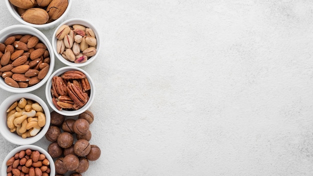 Free photo different kinds of nuts in white bowls copy space