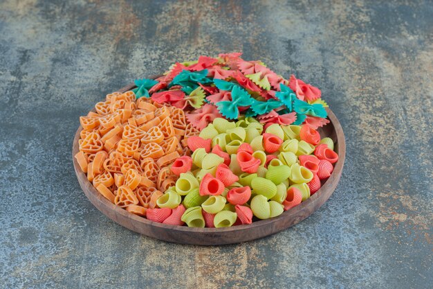 Different kinds of pasta in bowl, on the marble surface.