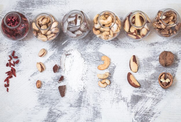 Различные орехи в баночках на светлом деревянном фоне, концепция здорового питания