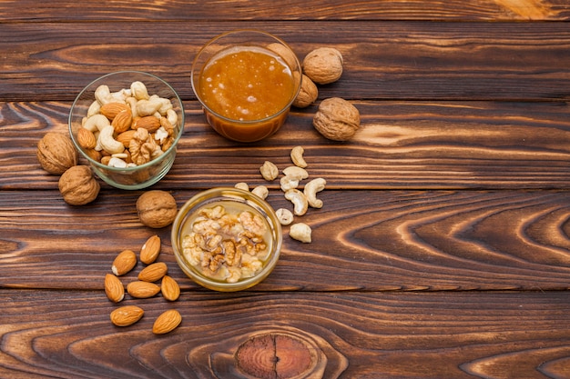 Free photo different nuts with honey on wooden table