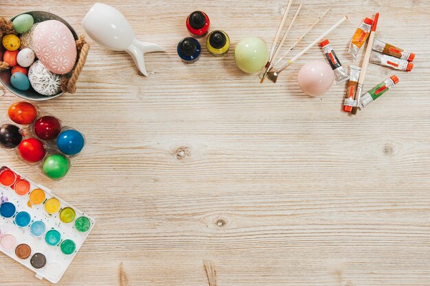 Different paints and colored eggs on table