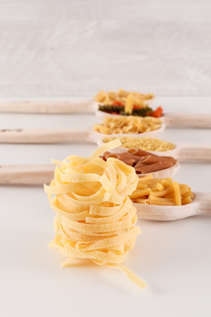 different pasta types in wooden spoons on the table