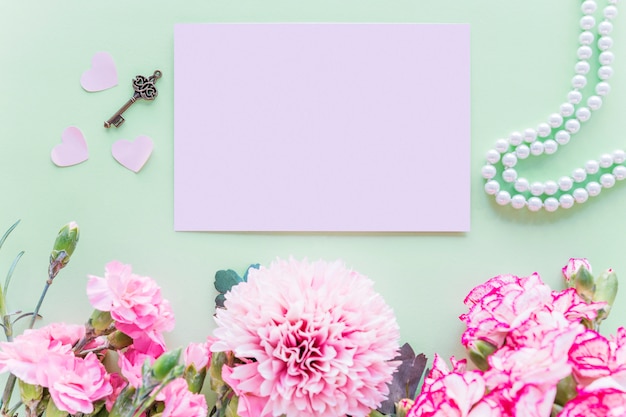 Foto gratuita fiori rosa differenti con carta sul tavolo verde