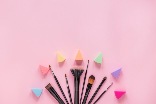 Different powder brushes with eye shadows on pink table 