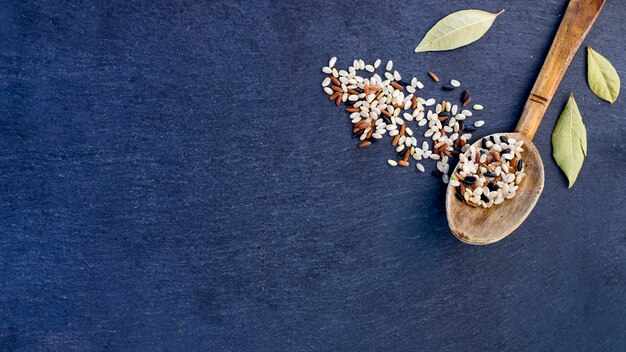 Different rice grains in wooden spoon on blue table