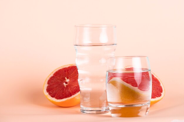 Different sized glasses of water with red oranges