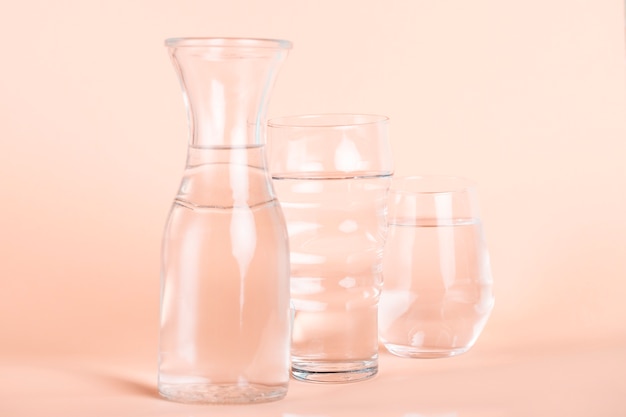 水と桃の背景を持つ異なるサイズのグラス