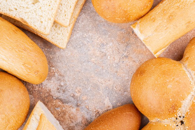 Different sliced and whole bread, on the marble background.