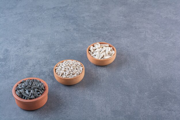 Different sunflower seeds in bowls , on the blue surface