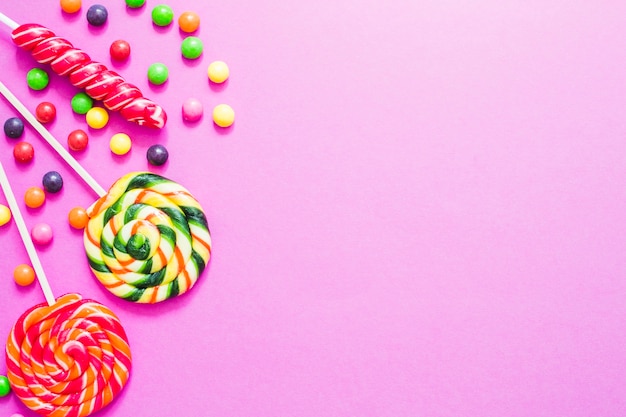 Different sweet candies on pink background