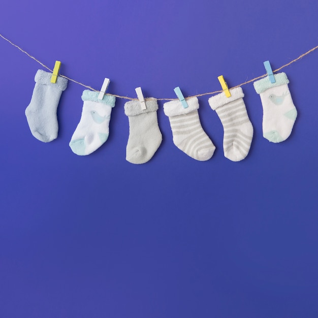 Different type of baby's sock hang on clothesline against blue backdrop