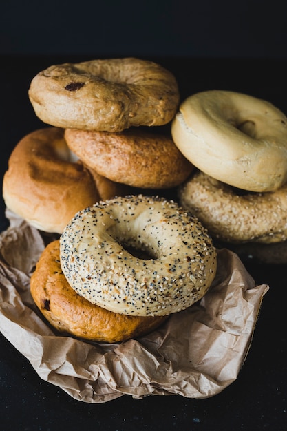 Different type of bagels on crumpled brown paper on black background