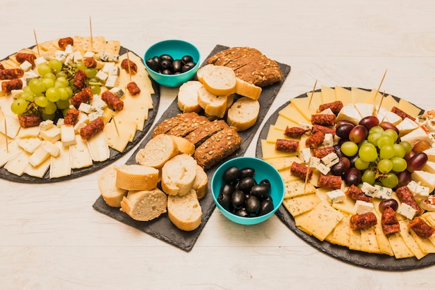 Разные виды ломтиков хлеба с оливками и сыром на деревянном столе