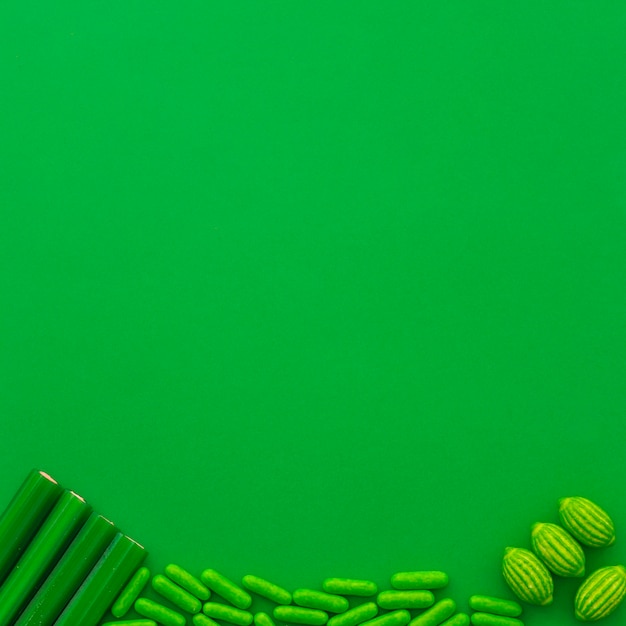 Different type of candies at the bottom of green background