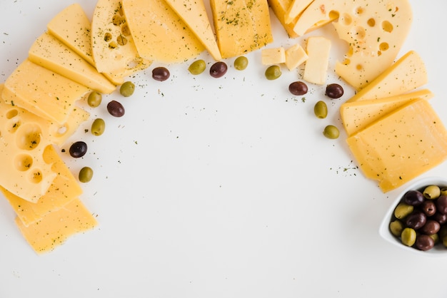 Different type of cheese slices with olives on white backdrop